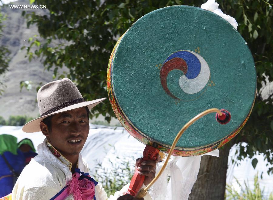 Farmers in holiday array carry scriptures while attending an Ongkor Festival prayer ceremony in Bomtoi Village, Dagze County, Lhasa, southwest China's Tibet Autonomous Region, July 1, 2014. By walking around farmlands, villagers of the Tibetan ethnic group pray for good harvests during the annual Ongkor Festival, or Bumper Harvest Festival. [Photo/Xinhua]