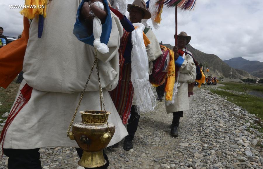 Farmers in holiday array carry scriptures while attending an Ongkor Festival prayer ceremony in Bomtoi Village, Dagze County, Lhasa, southwest China's Tibet Autonomous Region, July 1, 2014. By walking around farmlands, villagers of the Tibetan ethnic group pray for good harvests during the annual Ongkor Festival, or Bumper Harvest Festival. [Photo/Xinhua]