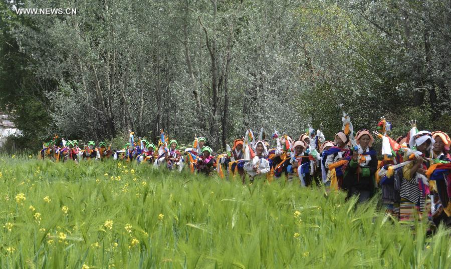 Farmers in holiday array carry scriptures while attending an Ongkor Festival prayer ceremony in Bomtoi Village, Dagze County, Lhasa, southwest China's Tibet Autonomous Region, July 1, 2014. By walking around farmlands, villagers of the Tibetan ethnic group pray for good harvests during the annual Ongkor Festival, or Bumper Harvest Festival. [Photo/Xinhua]