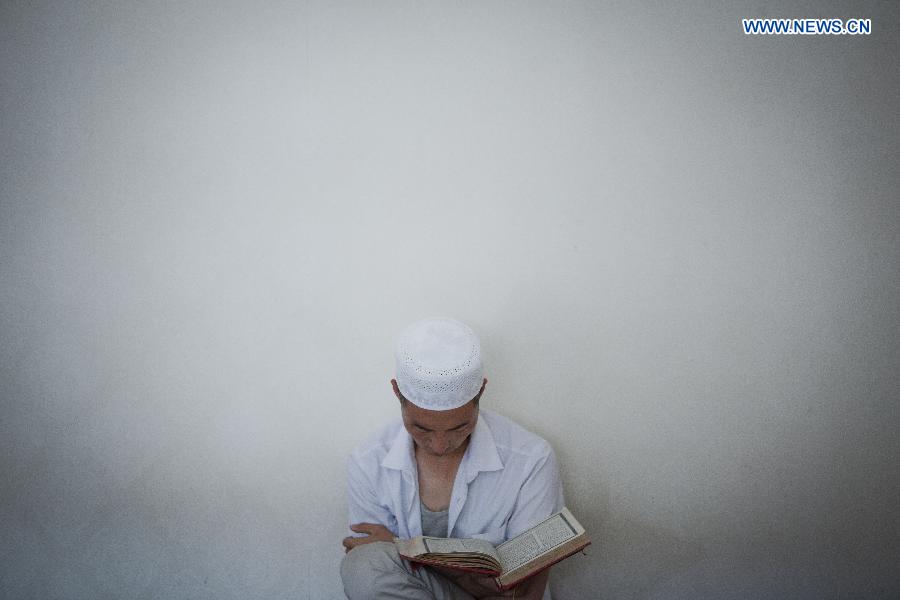 A Muslim reads scriptures at the Qingzhenzhongsi Mosque in Yinchuan, capital of Ningxia Hui Autonomous Region, July 3, 2014. Built in 1931, the mosque was located in downtown Yinchuan and known for its ancient-style architectures. [Photo/Xinhua]