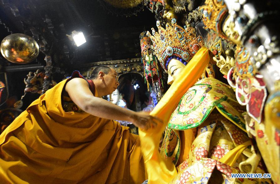 The 11th Panchen Lama Bainqen Erdini Qoigyijabu, who is also a member of the Standing Committee of the Chinese People's Political Consultative Conference (CPPCC) National Committee, presents a hada, a strip of raw silk, to a Buddha statue at the Jokhang Temple in Lhasa, capital of southwest China's Tibet Autonomous Region, July 2, 2014. The Panchen Lama made a research and inspection tour in Lhasa in recent days. [Photo/Xinhua]