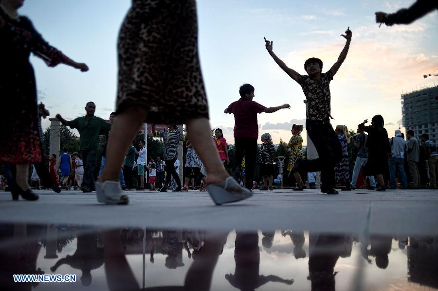 Citizens dance at the Maigaiti Dolan Culture Square in Maigaiti County, northwest China's Xingjiang Uygur Autonomous Region, June 29, 2014. Maigaiti County, known as the 'home of Dolan', has taken measures to protect and inherit the world intangible cultural heritage 'Dolan Muqam' since April 2012. [Photo/Xinhua]