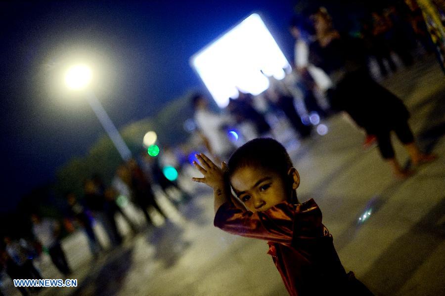 A child dances at the Maigaiti Dolan Culture Square in Maigaiti County, northwest China's Xingjiang Uygur Autonomous Region, June 29, 2014. Maigaiti County, known as the 'home of Dolan', has taken measures to protect and inherit the world intangible cultural heritage 'Dolan Muqam' since April 2012. [Photo/Xinhua]