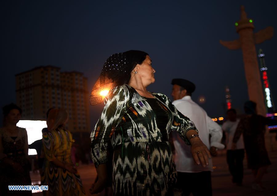 Citizens dance at the Maigaiti Dolan Culture Square in Maigaiti County, northwest China's Xingjiang Uygur Autonomous Region, June 29, 2014. Maigaiti County, known as the 'home of Dolan', has taken measures to protect and inherit the world intangible cultural heritage 'Dolan Muqam' since April 2012. [Photo/Xinhua]