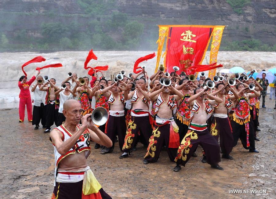 Performers play suona horns near the Hukou Waterfall of the Yellow River, north China's Shanxi Province, July 9, 2014. [Photo/Xinhua]