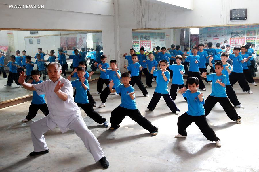 Students learn to play Tai Chi in Wenxian County of Jiaozuo City, central China's Henan Province, July 8, 2014. Many primary and middle school students in Wenxian took part in Tai Chi training classes during the summer vacation. [Photo/Xinhua]