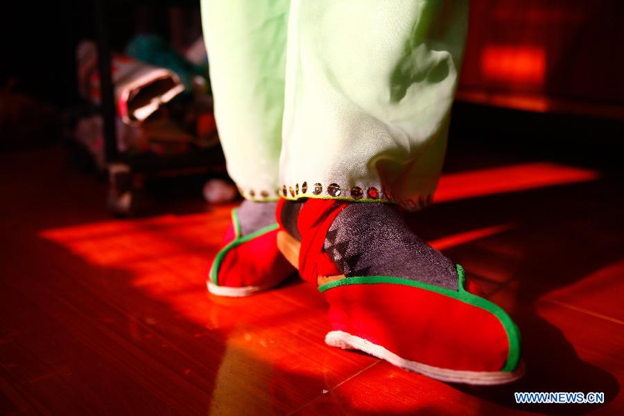 Flower Drum Dance performer Shi Chuncai puts on his performing shoes in Lianhua Village, Huaiyuan County of Bengbu City, east China's Anhui Province, Dec 3, 2014. [Photo/Xinhua]