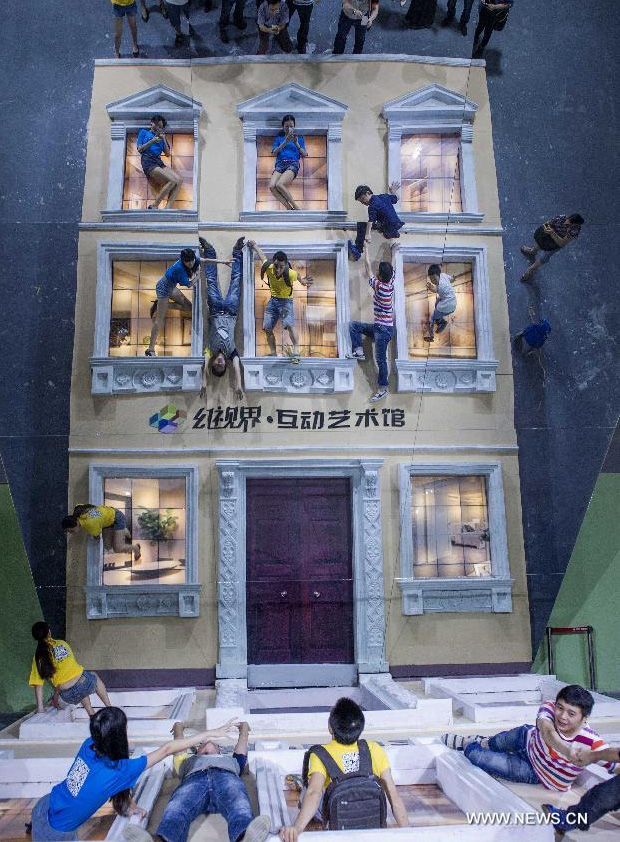 Visitors pose for photo during a 3D painting exhibition in southwest China's Chongqing, June 26, 2014. Over 200 pieces of 3D painting were on display. [Photo/Xinhua]