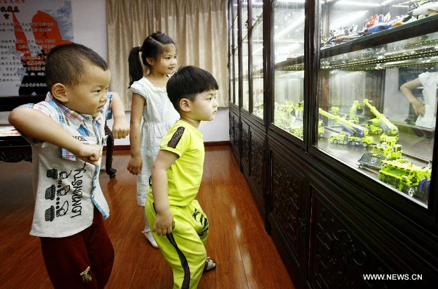 Children look at toys displayed at an old toy exhibition in east China's Shanghai, July 2, 2014. The toys presented on the exhibition, from the collections of 18 collectors, remind visitors born in the 1970s and the 1980s of their childhood. [Photo/Xinhua]