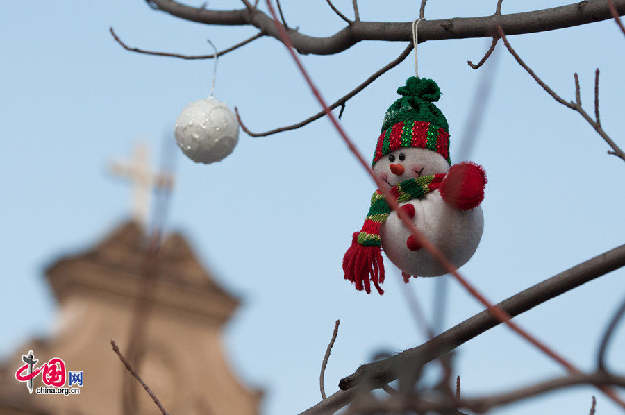 The Cathedral of the Immaculate Conception (colloquially known as the Xuanwumen Church, the South Church, or Nantang) in Beijing places a handful of Christmas-themed toys on the treee twigs before the church gate on Christmas Day, Dec. 25. [Photo by Chen Boyuan / China.org.cn]