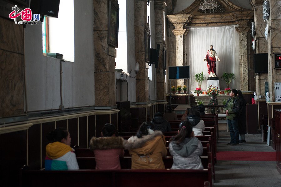 Believers pray before the statue of Jesus Christ in the Cathedral of the Immaculate Conception (colloquially known as the Xuanwumen Church, the South Church, or Nantang) in Beijing on the afternoon of Dec. 25, 2013, the Christmas Day. [Photo by Chen Boyuan / China.org.cn]