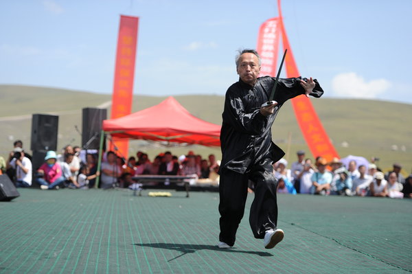 A martial arts master performs with a sword during the Tianshan Mountain Cultural Week in Tekes county, August 3, 2013. 